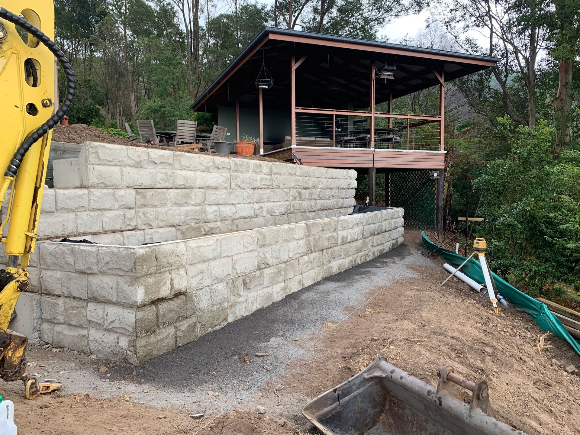 A Brick Wall Is In Front Of A Building With Trees In The Background — Bennett's Environmental In South Nowra, NSW