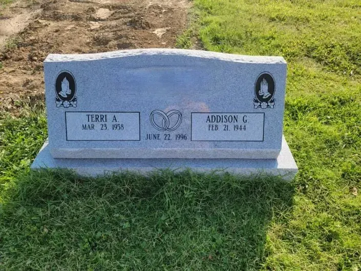 A gravestone in a cemetery with two people 's names on it.