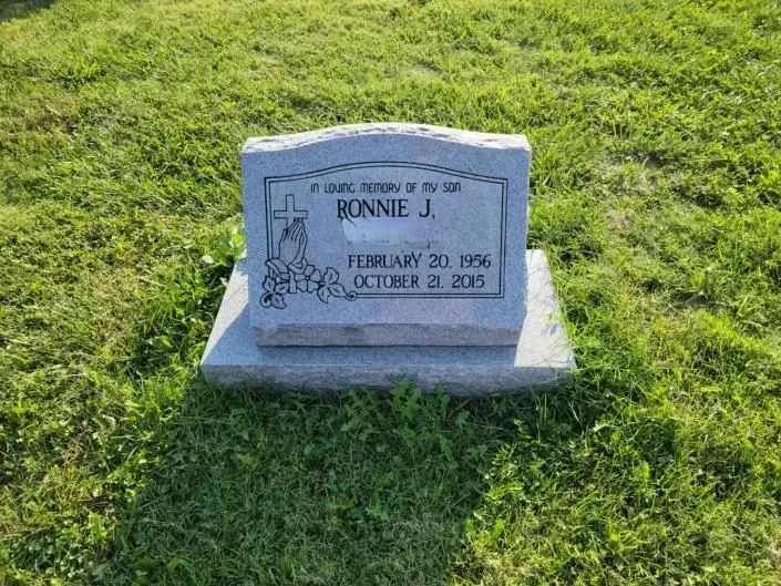A gravestone for bonnie j. is sitting in the middle of a grassy field.