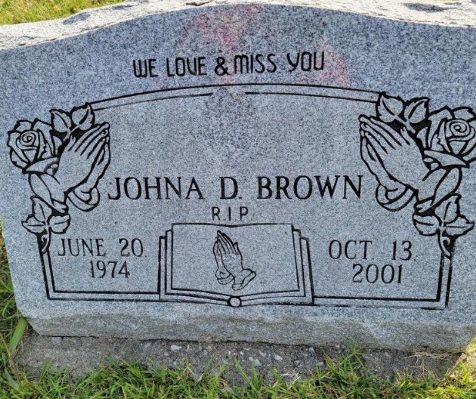 A gravestone for johna d brown with roses and praying hands on it.