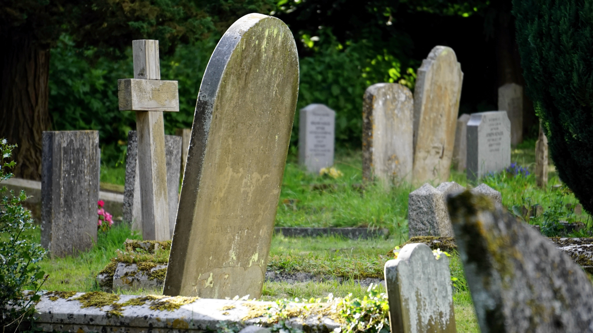 A cemetery with a lot of graves and a cross in the middle.