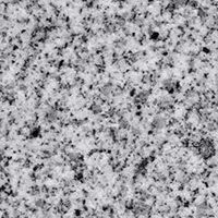 A close up of a white granite counter top with black spots.