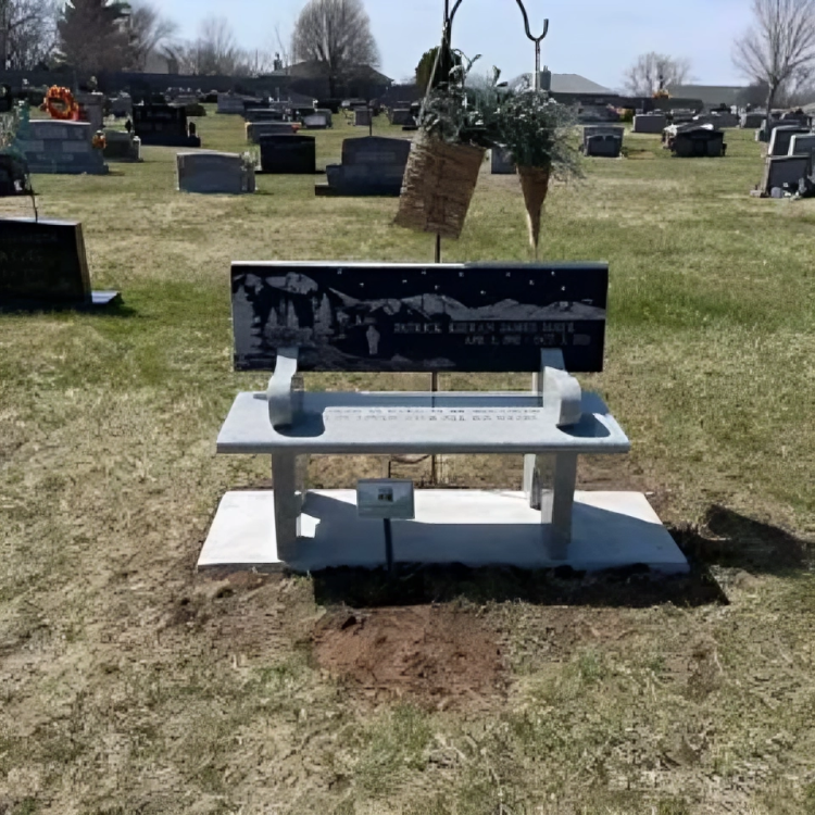 A bench in a cemetery with a picture of mountains on it