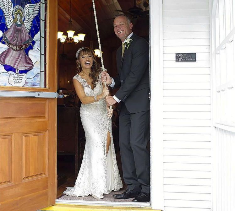 A bride and groom are standing in the doorway of a church