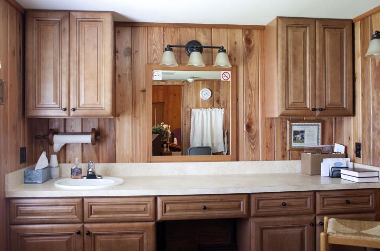 A bathroom with wood paneling and a sink and mirror