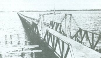 A black and white photo of a bridge over a body of water.