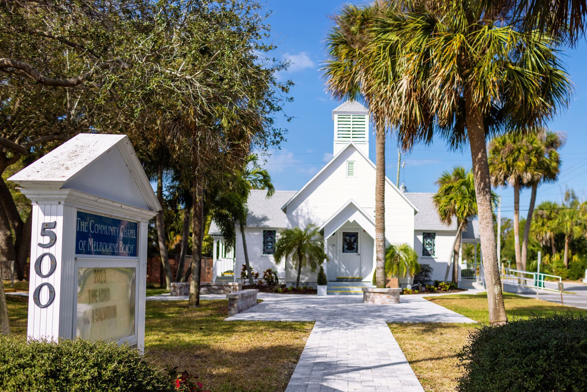 A white church with palm trees in front of it