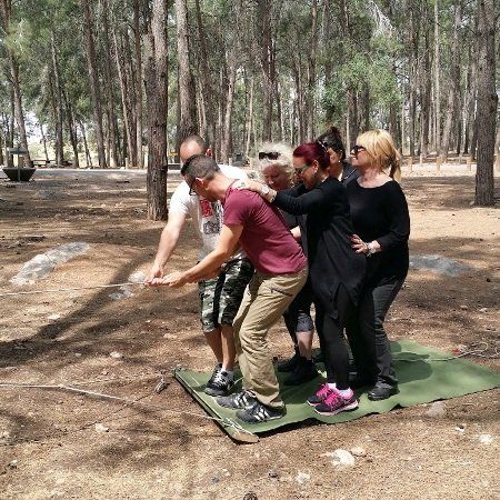 קבוצה של אנשים עומדת על מחצלת ביער.