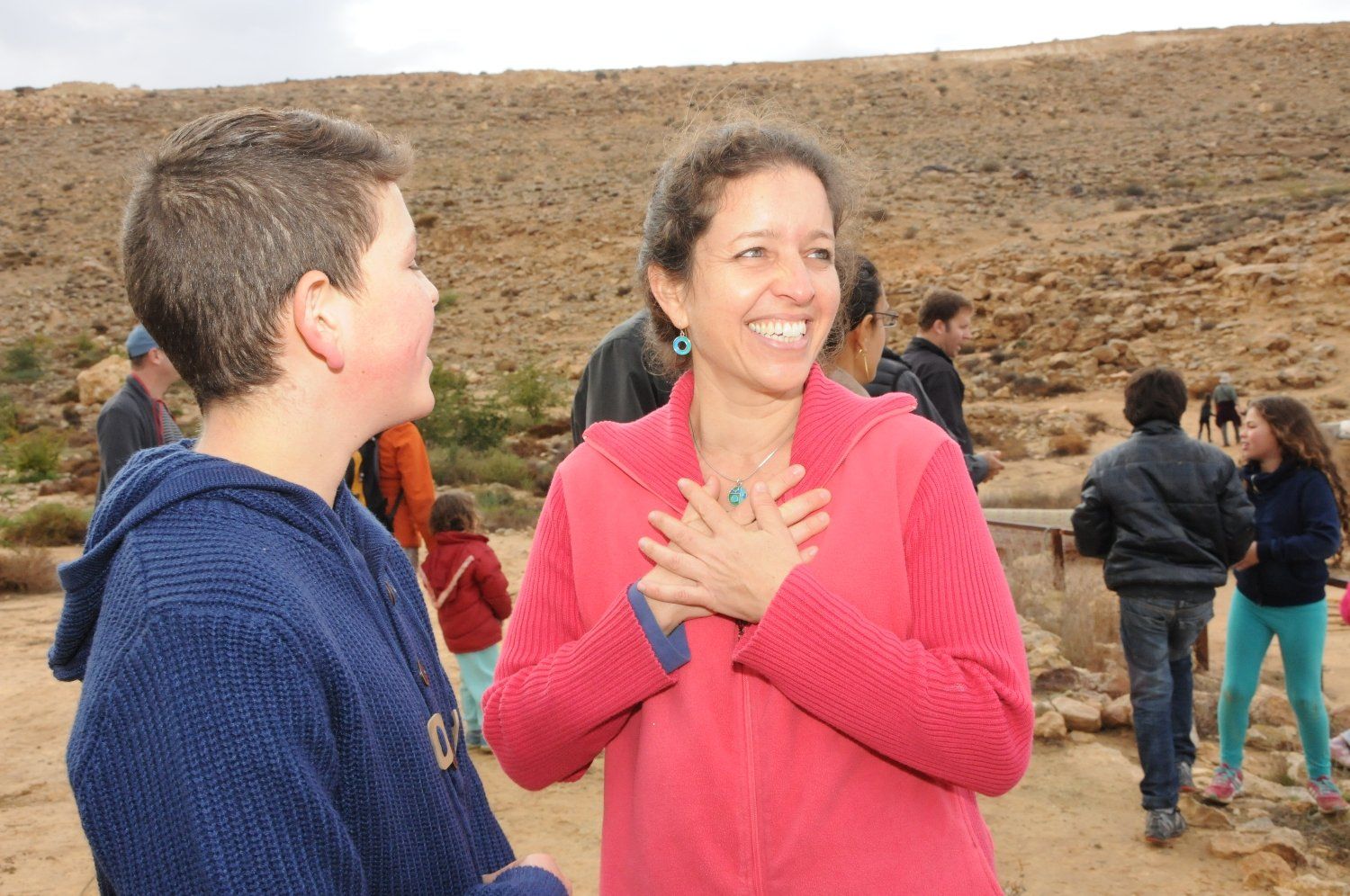 אישה עם ז'קט ורוד מדברת עם ילד עם קפוצ'ון כחול.