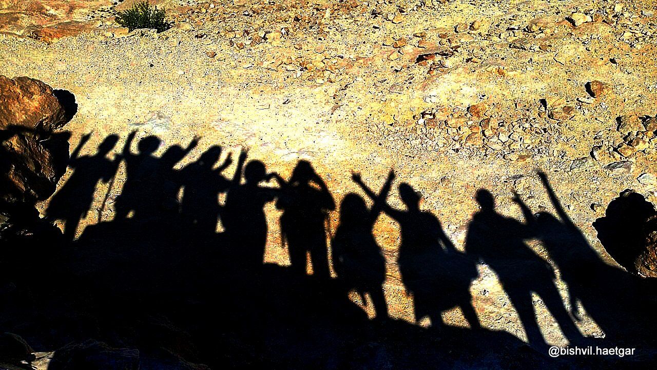 קבוצה של אנשים עומדים זה ליד זה עם הידיים באוויר.