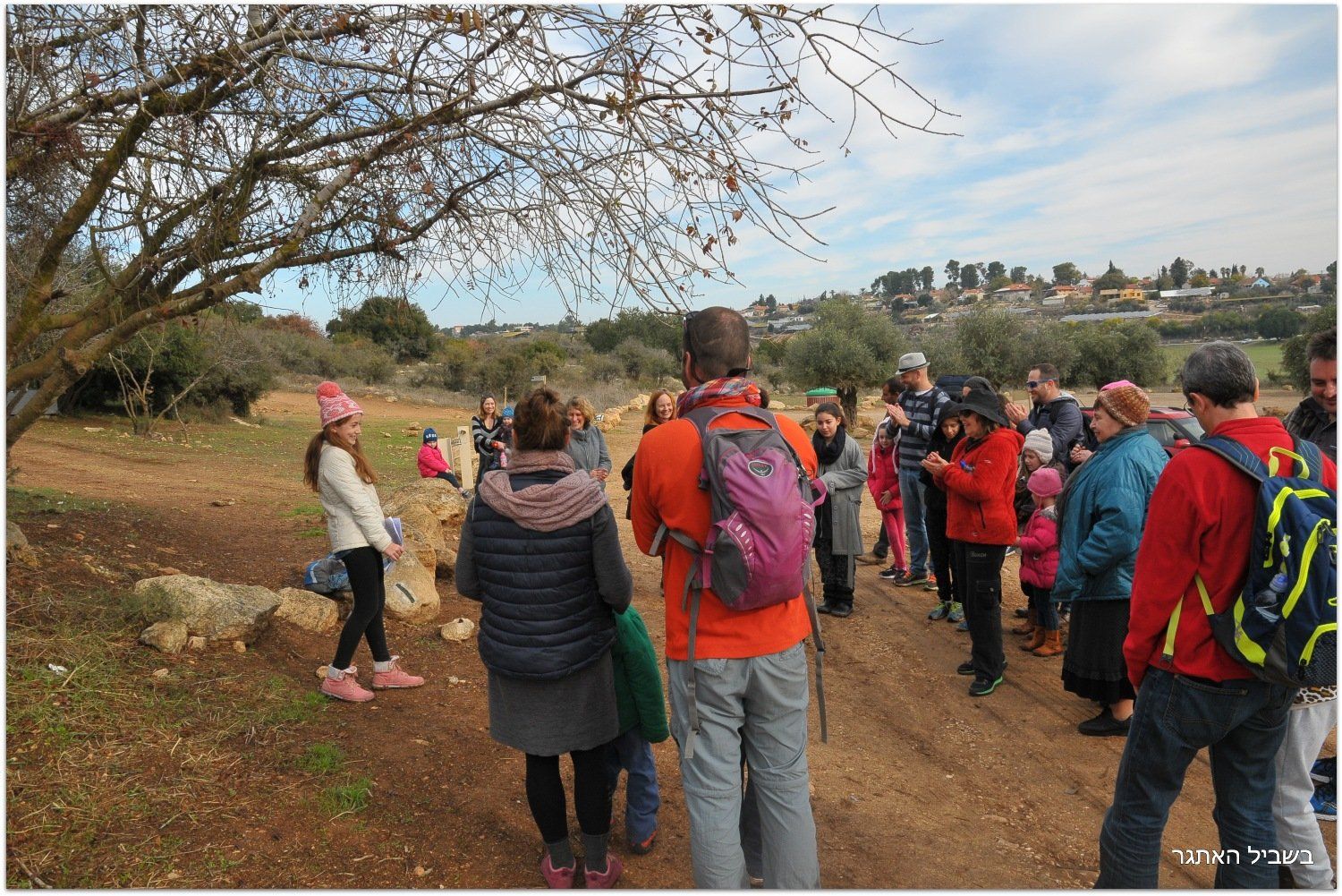 קבוצה של אנשים עומדת בשדה ומשוחחת זה עם זה.