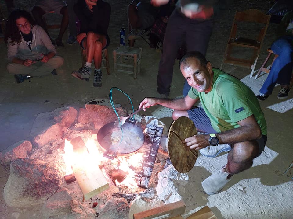 גבר בחולצה ירוקה כורע ברך מול מדורה