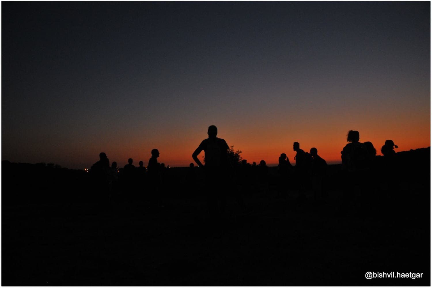 קבוצת אנשים מצטלמת על רקע שמי השקיעה