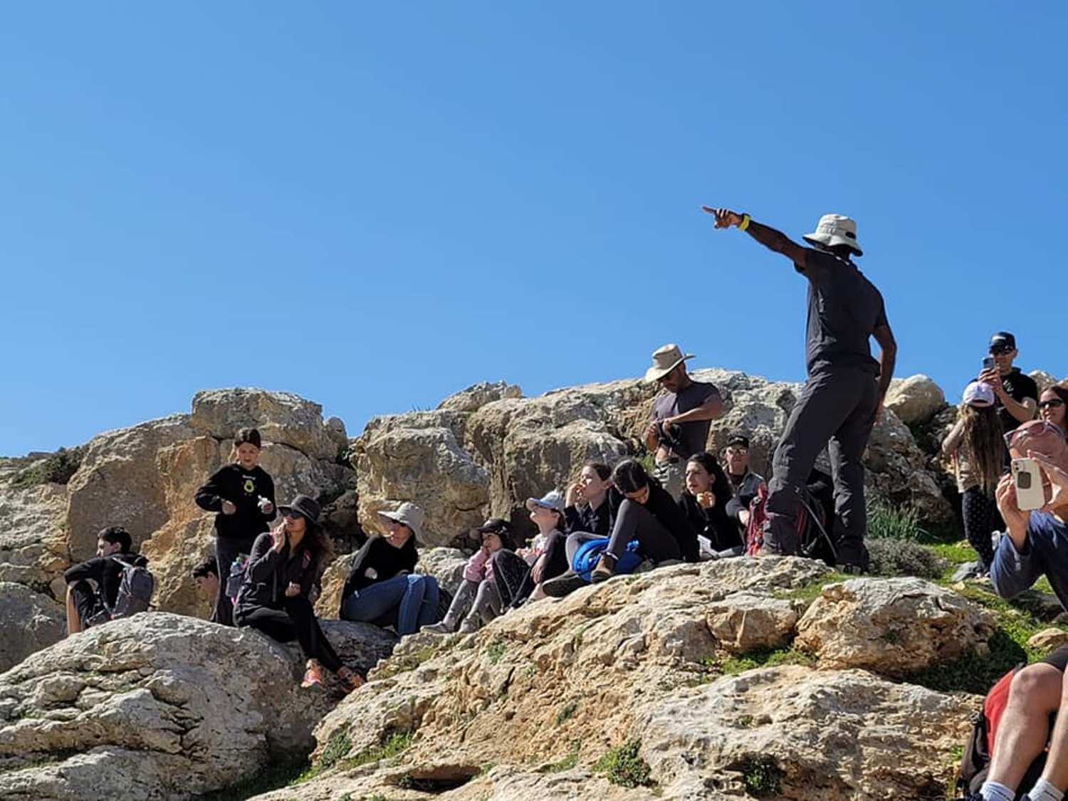 קבוצת אנשים יושבת על ראש גבעה סלעית.