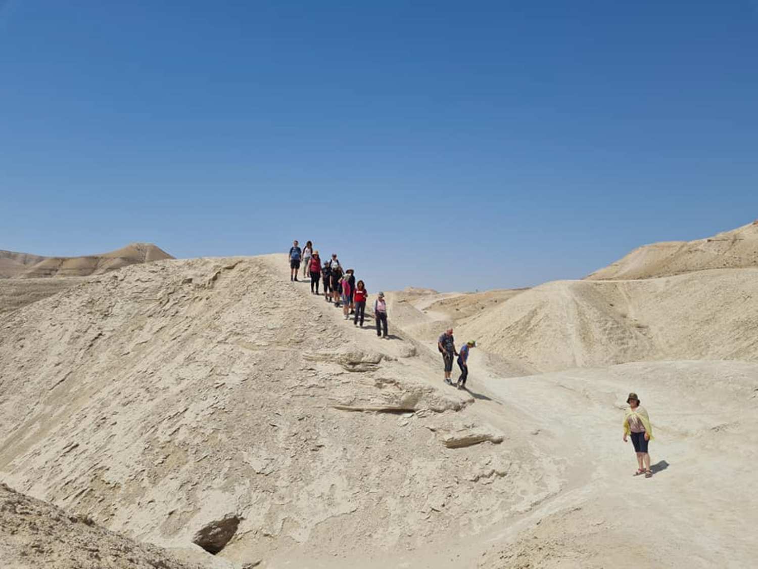 קבוצה של אנשים צועדת במעלה גבעה במדבר.