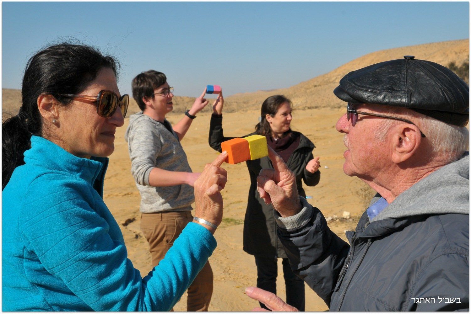 קבוצת אנשים עומדת במדבר ומשוחחת זה עם זה