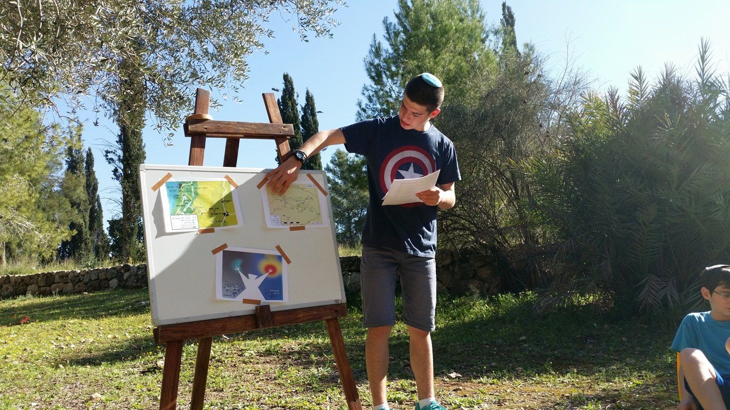 ילד בחולצת קפטן אמריקה עומד מול לוח לבן.