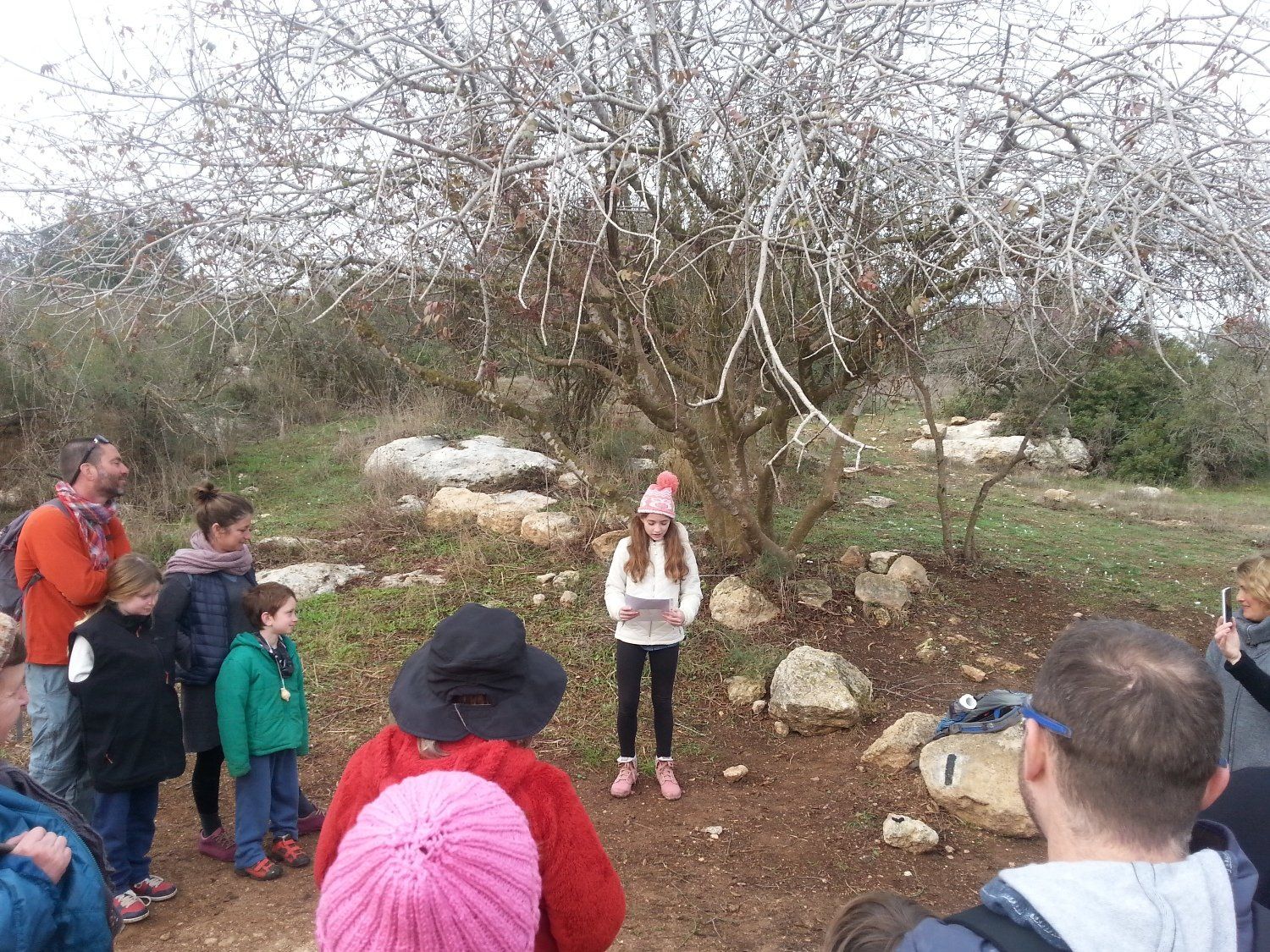 קבוצת אנשים עומדת סביב עץ בשדה.