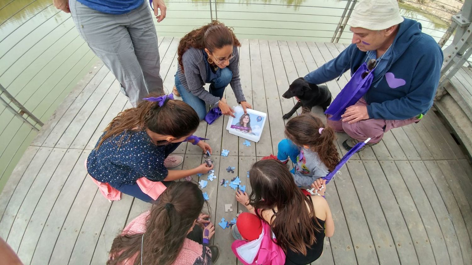 קבוצת ילדים יושבת במעגל על דק עץ.