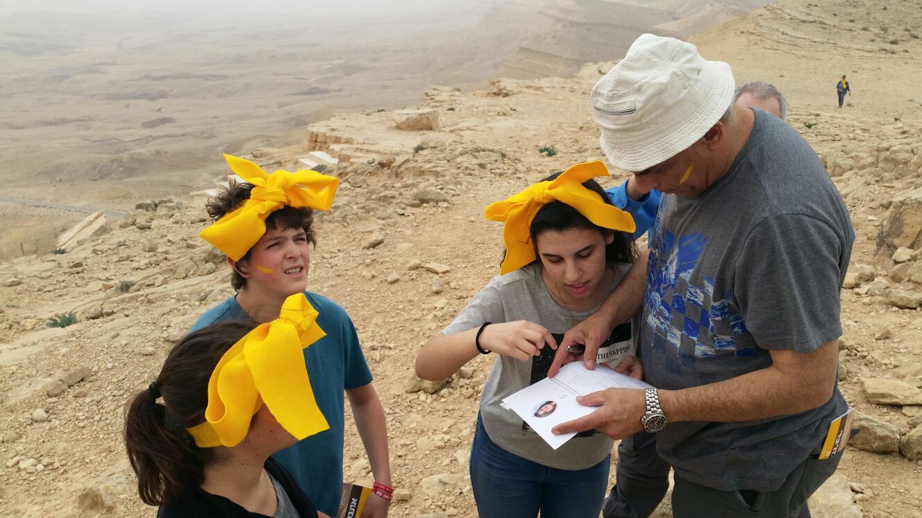 קבוצה של אנשים עומדת במדבר ומסתכלת על מפה.