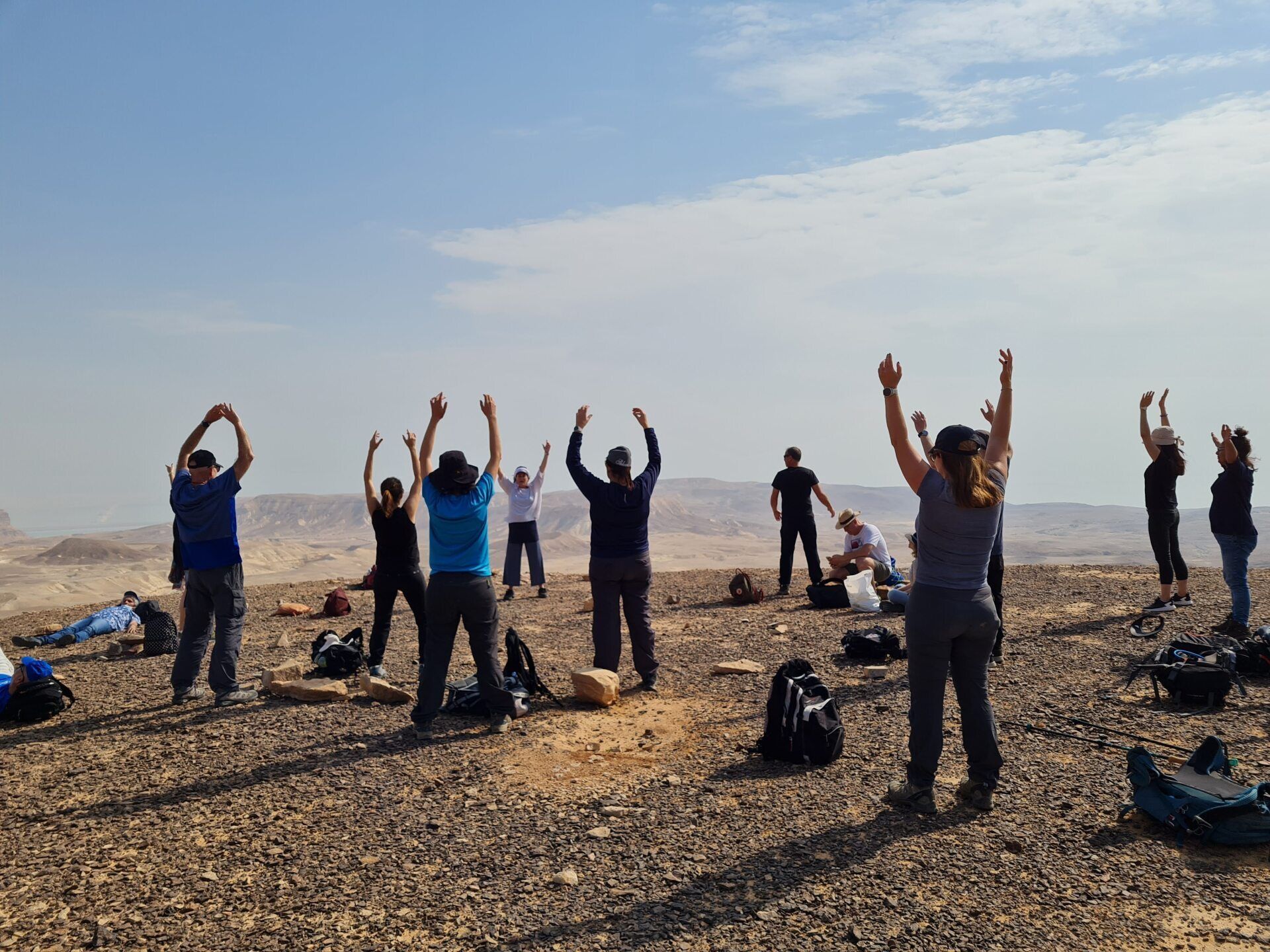 קבוצת אנשים עומדת במדבר עם זרועותיהם באוויר.
