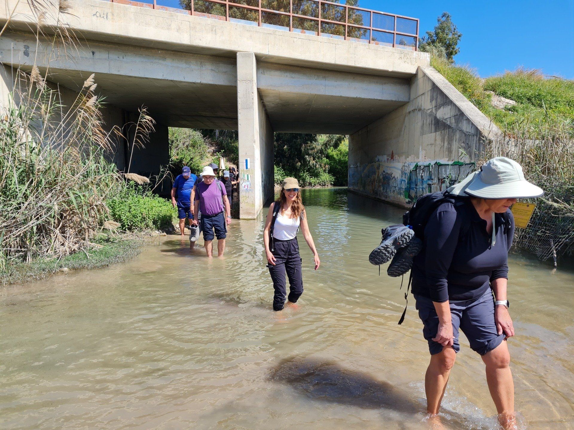 קבוצה של אנשים צועדת בנהר מתחת לגשר.