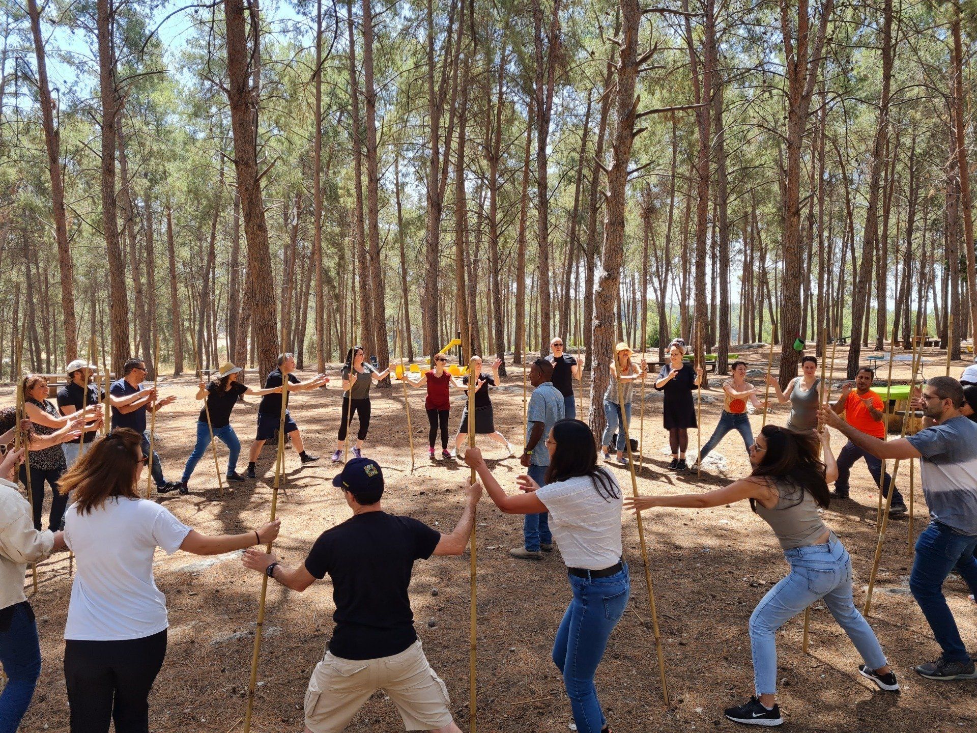קבוצת אנשים עומדת במעגל ביער ומחזיקים ידיים.