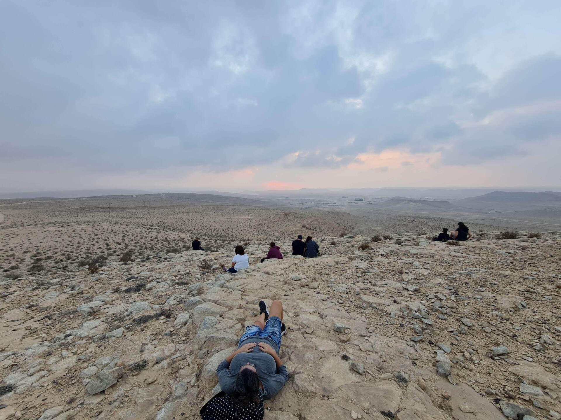 קבוצת אנשים שוכבת על ראש גבעה סלעית במדבר.