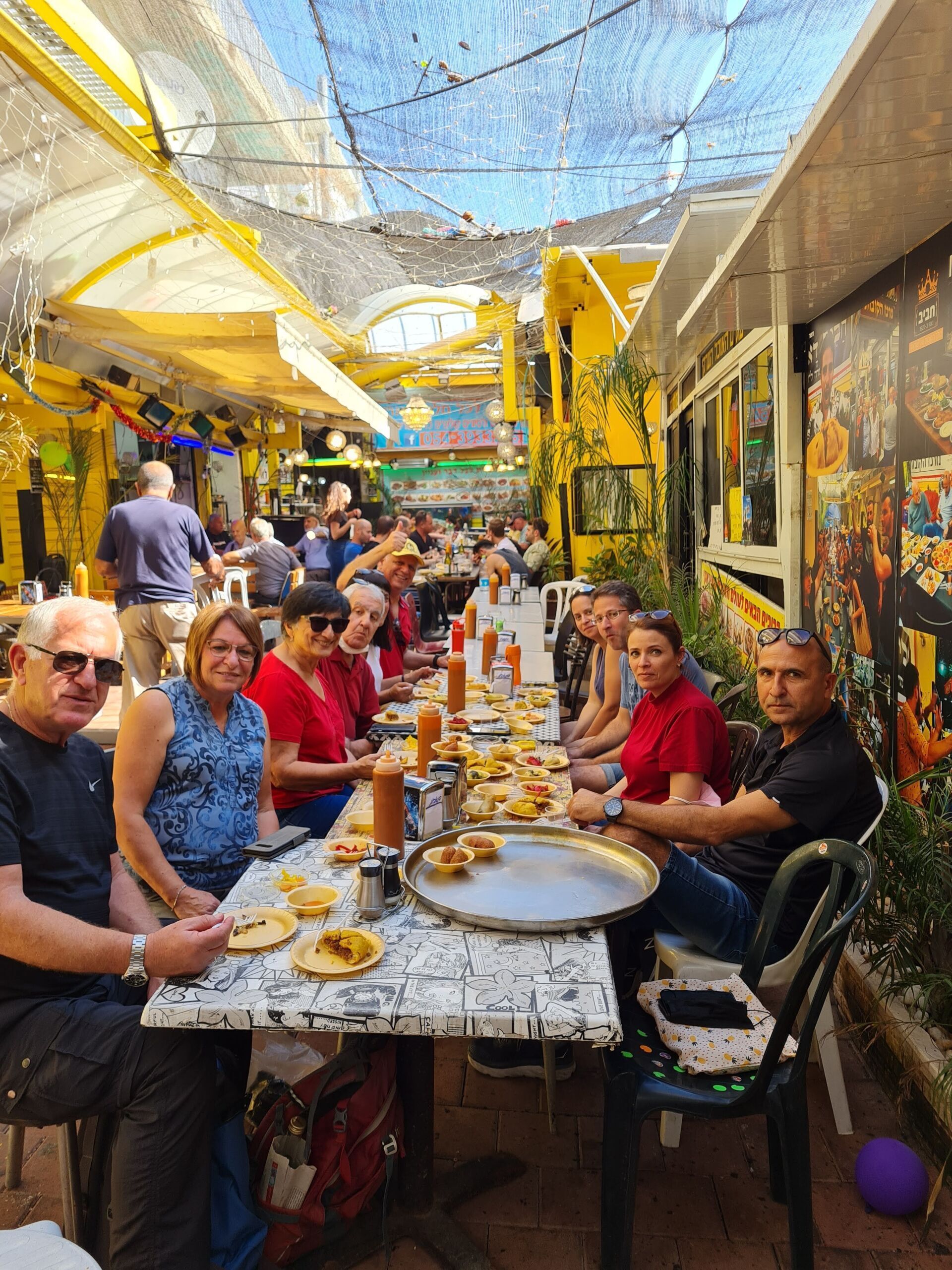 קבוצה של אנשים יושבים ליד שולחן ארוך ואוכלים אוכל.