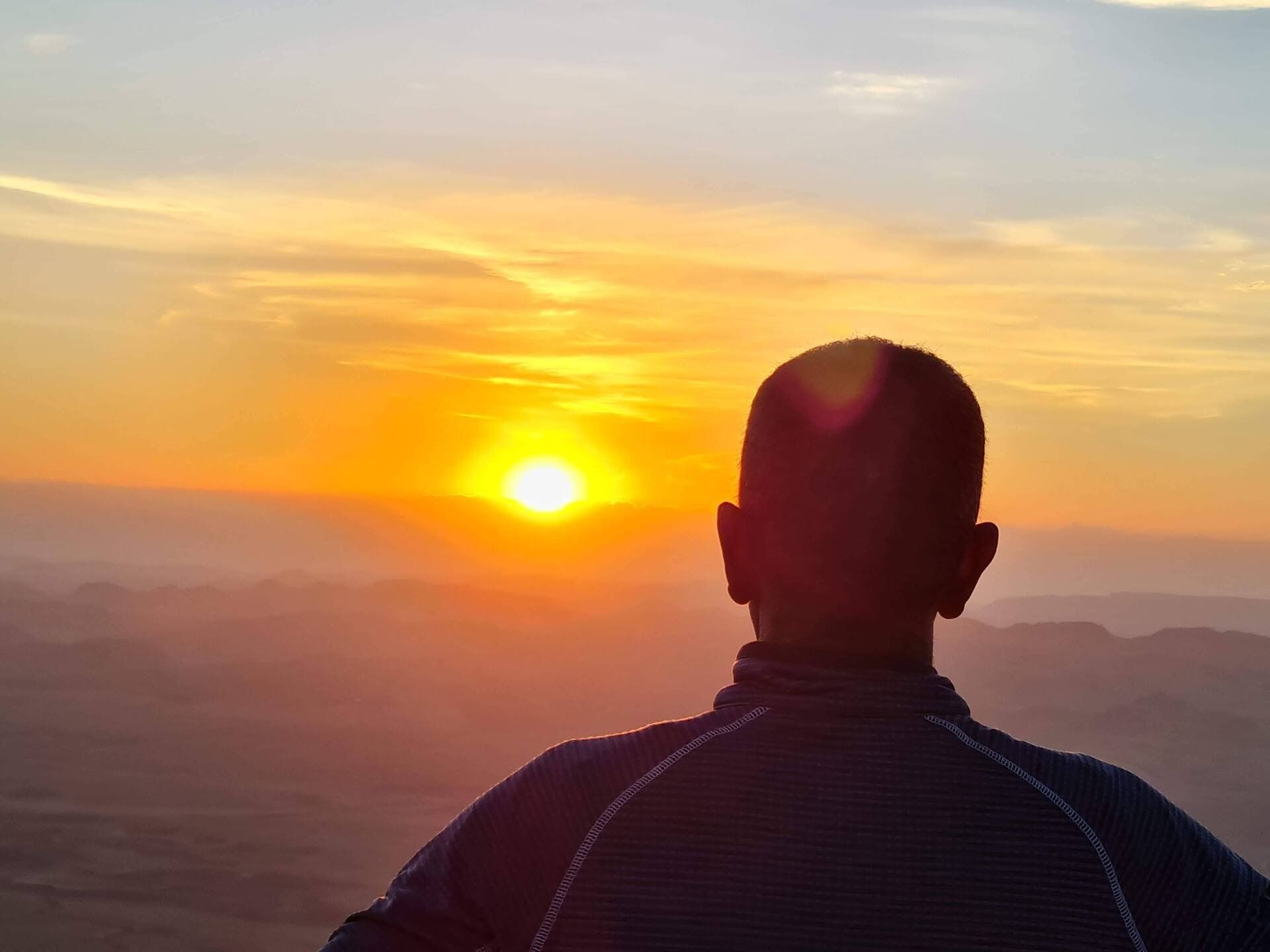 גבר במעיל כחול מסתכל על השקיעה