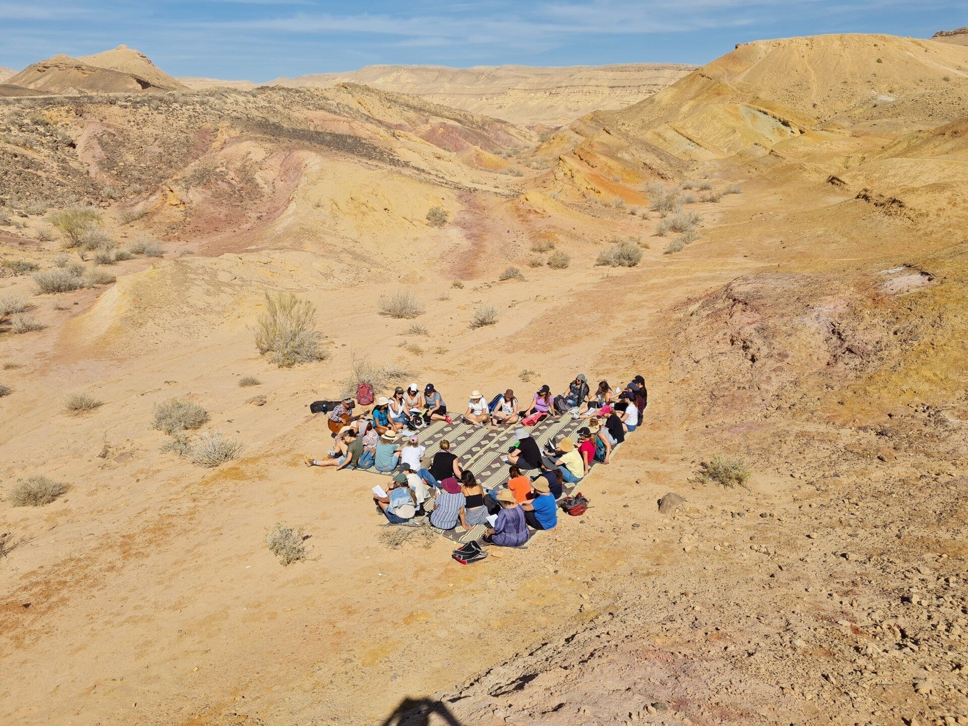 קבוצת אנשים יושבת במעגל במדבר.