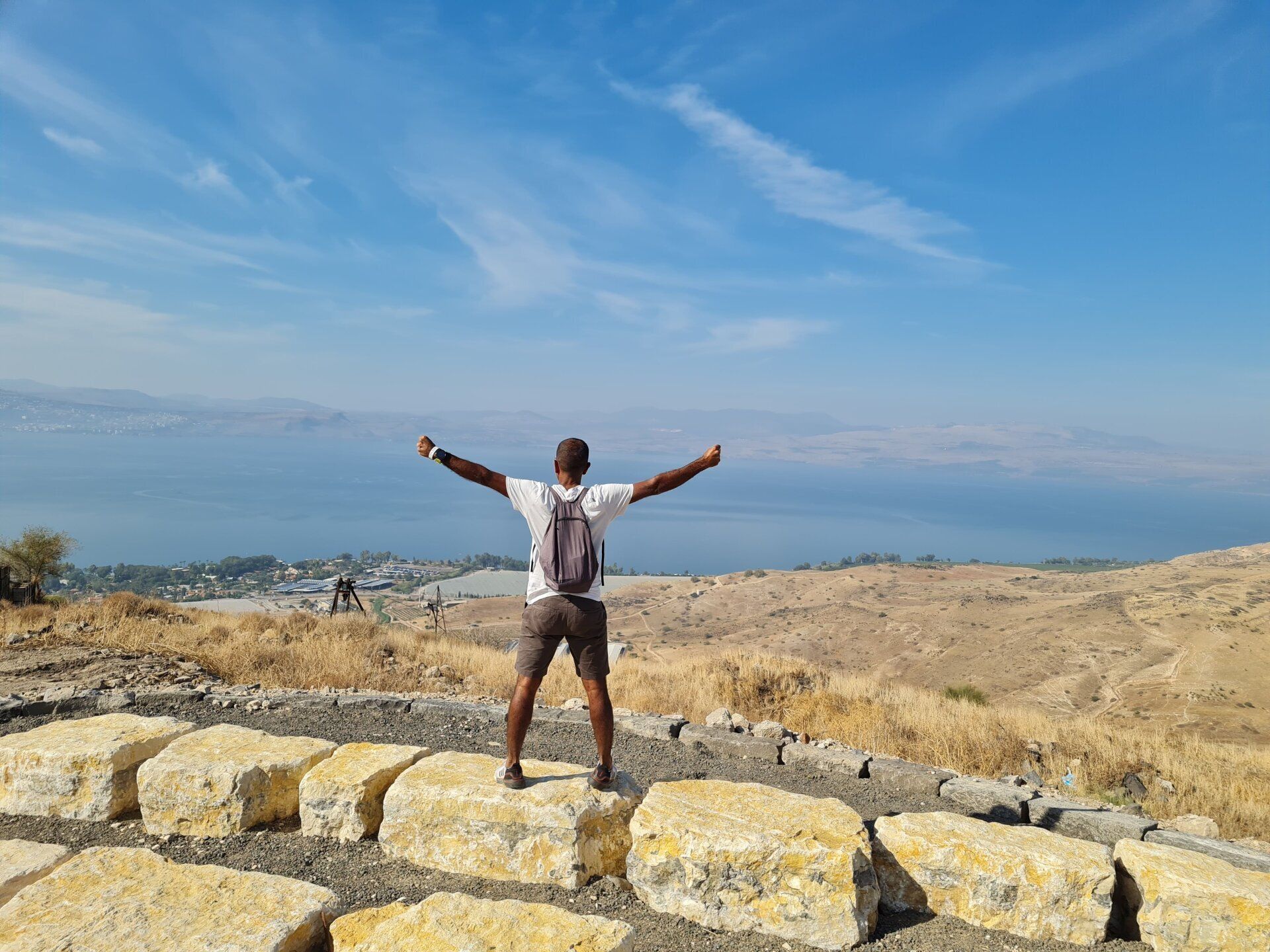 גבר עומד על סלע עם זרועותיו פרושות.