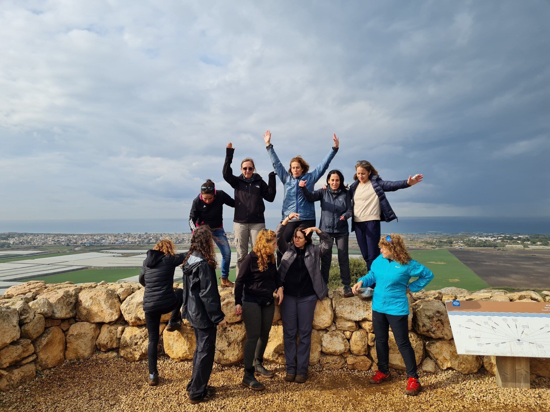 קבוצה של אנשים מצטלמים על גבי קיר אבן.