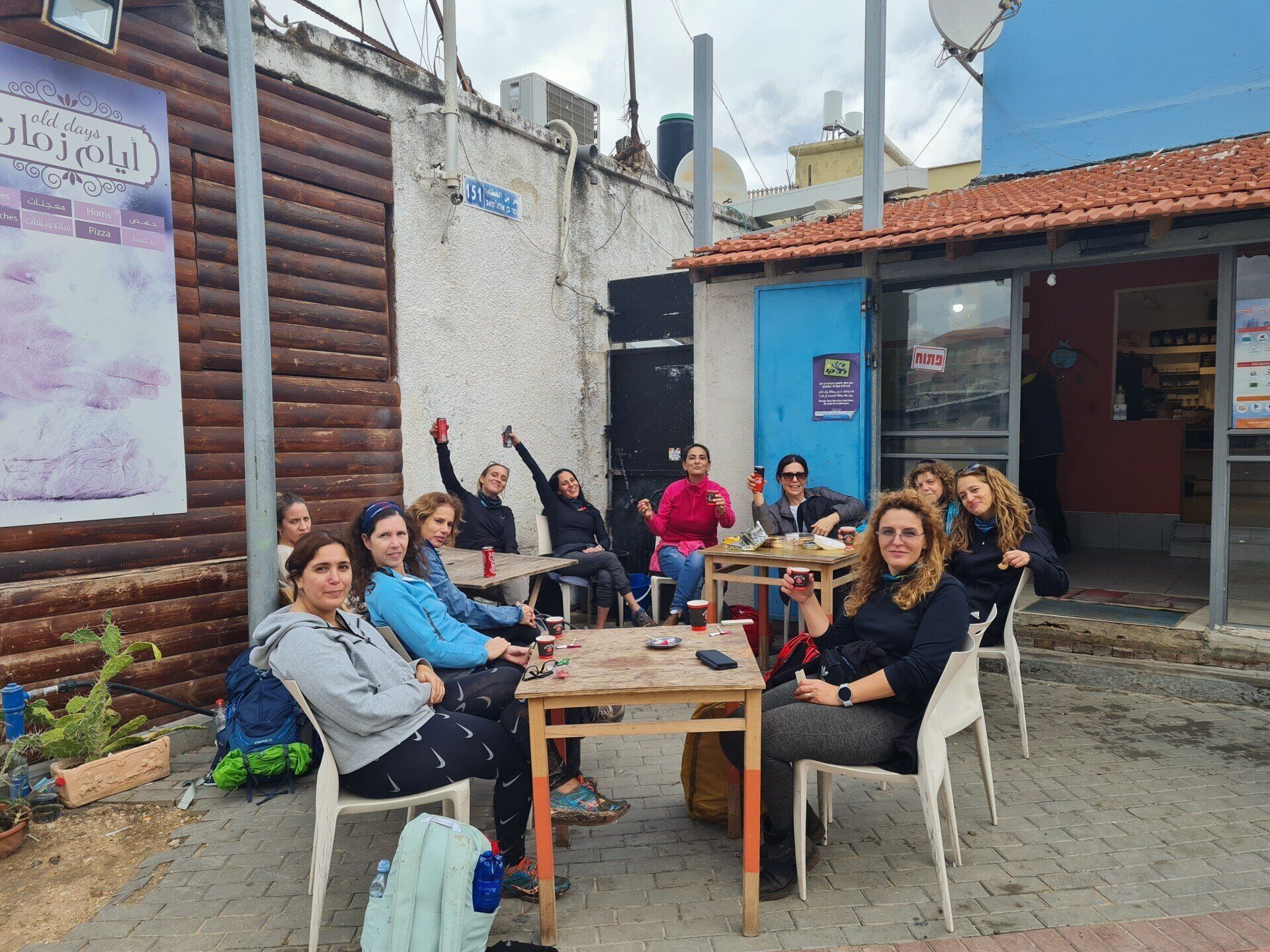 קבוצת נשים יושבת ליד שולחנות מחוץ לבניין.