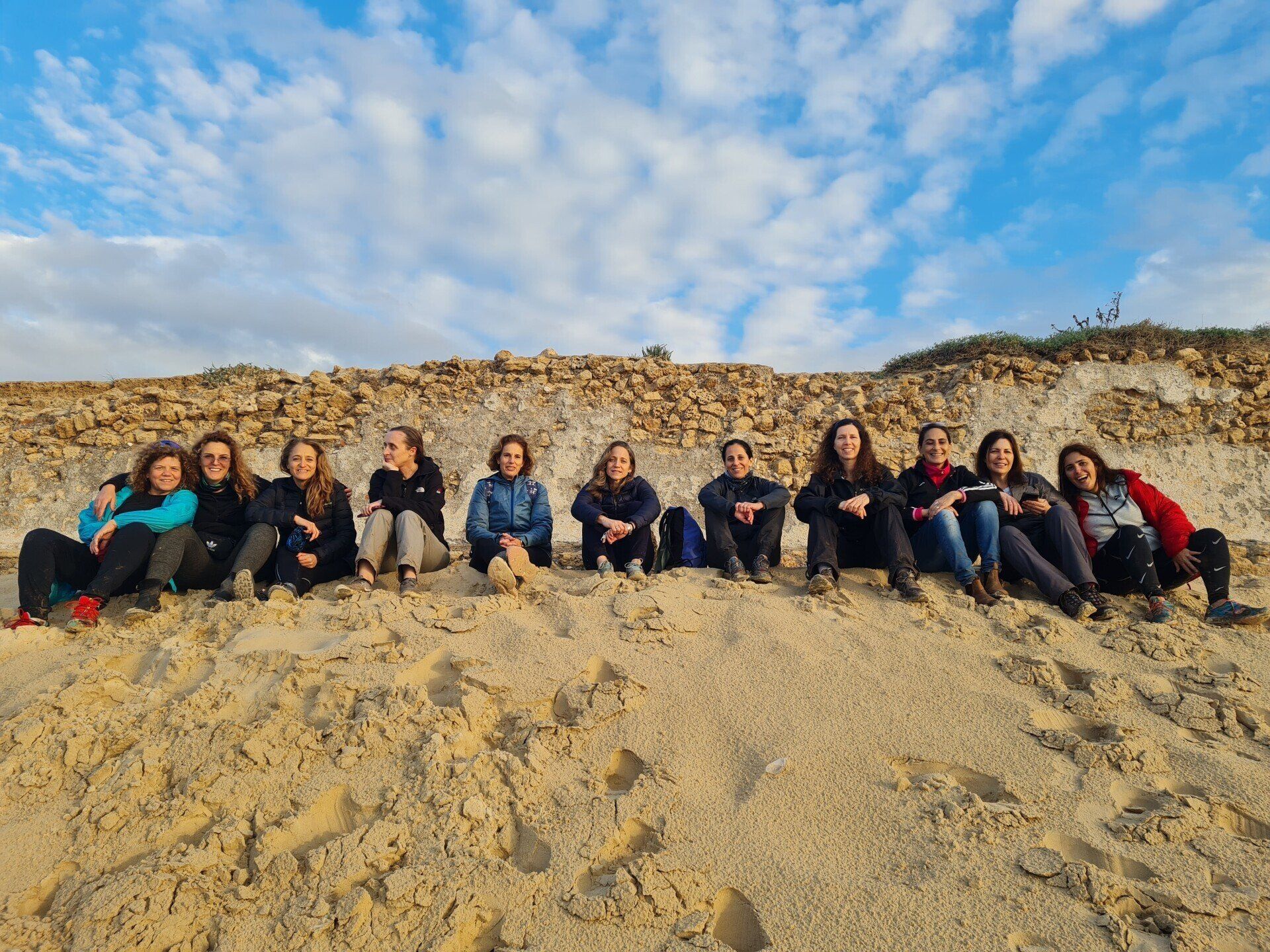 קבוצת אנשים יושבת על גבי דיונת חול.