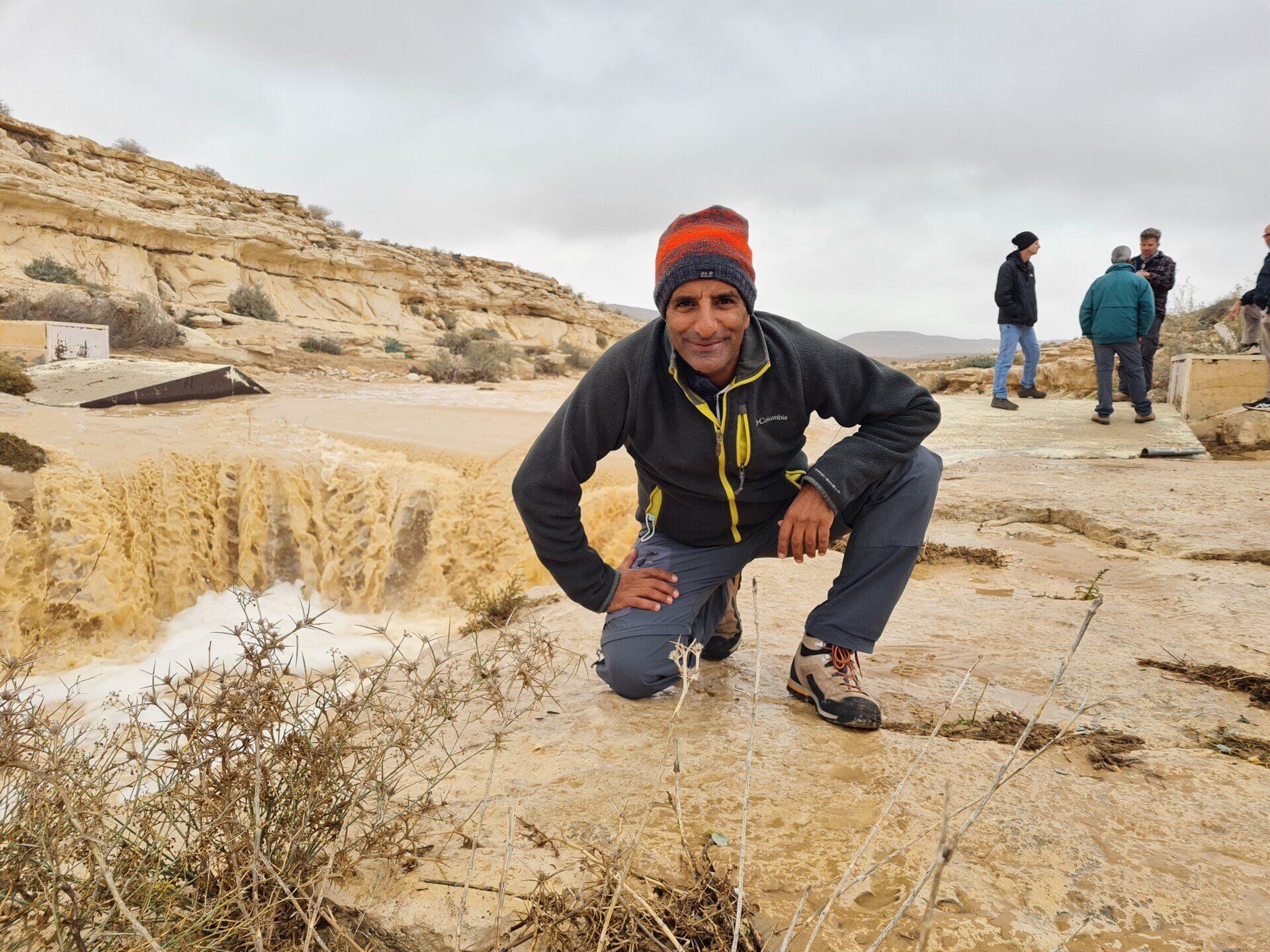 אדם כורע על סלע מול מפל.