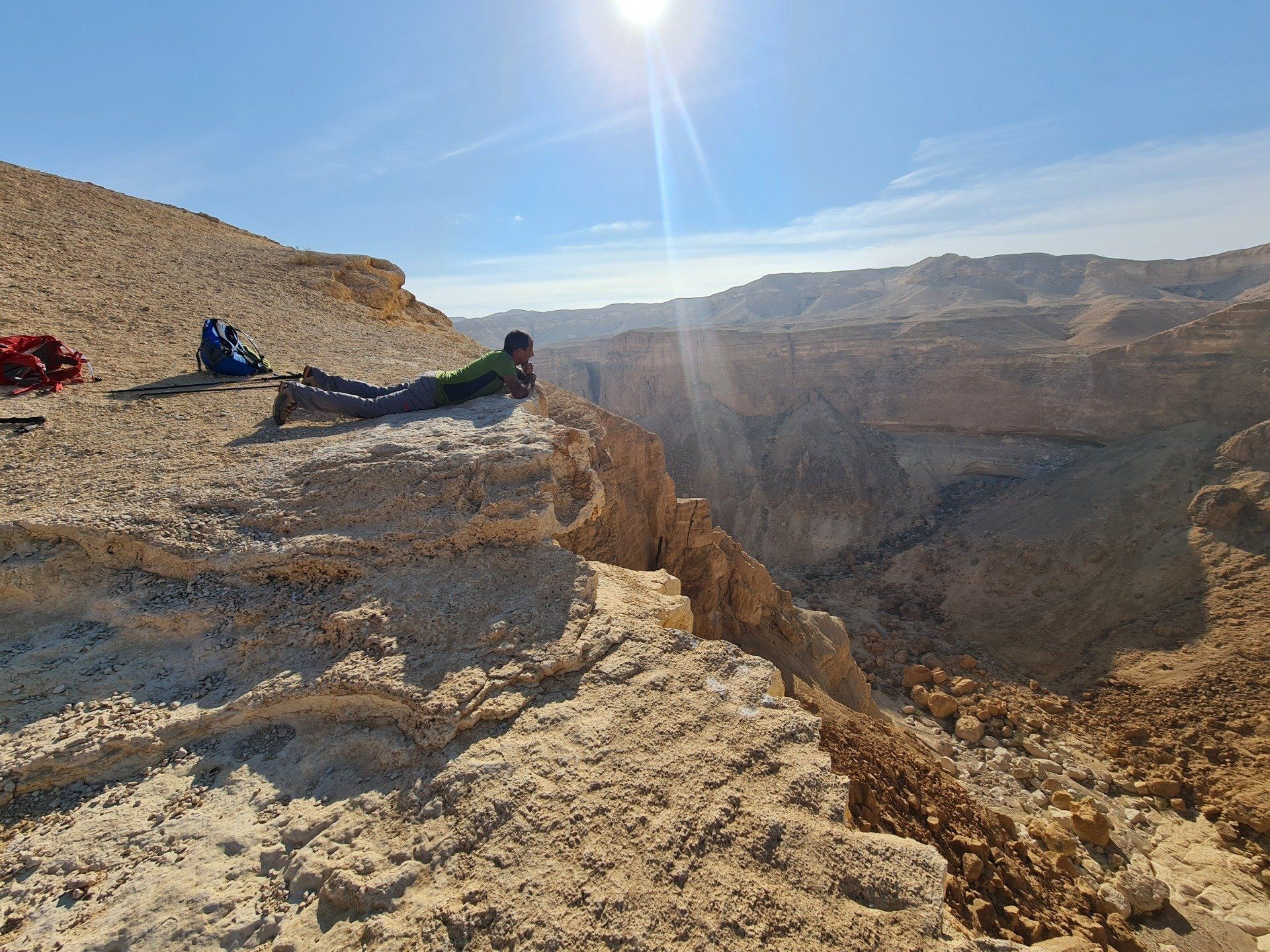 אדם שוכב על קצה צוק המשקיף על קניון.