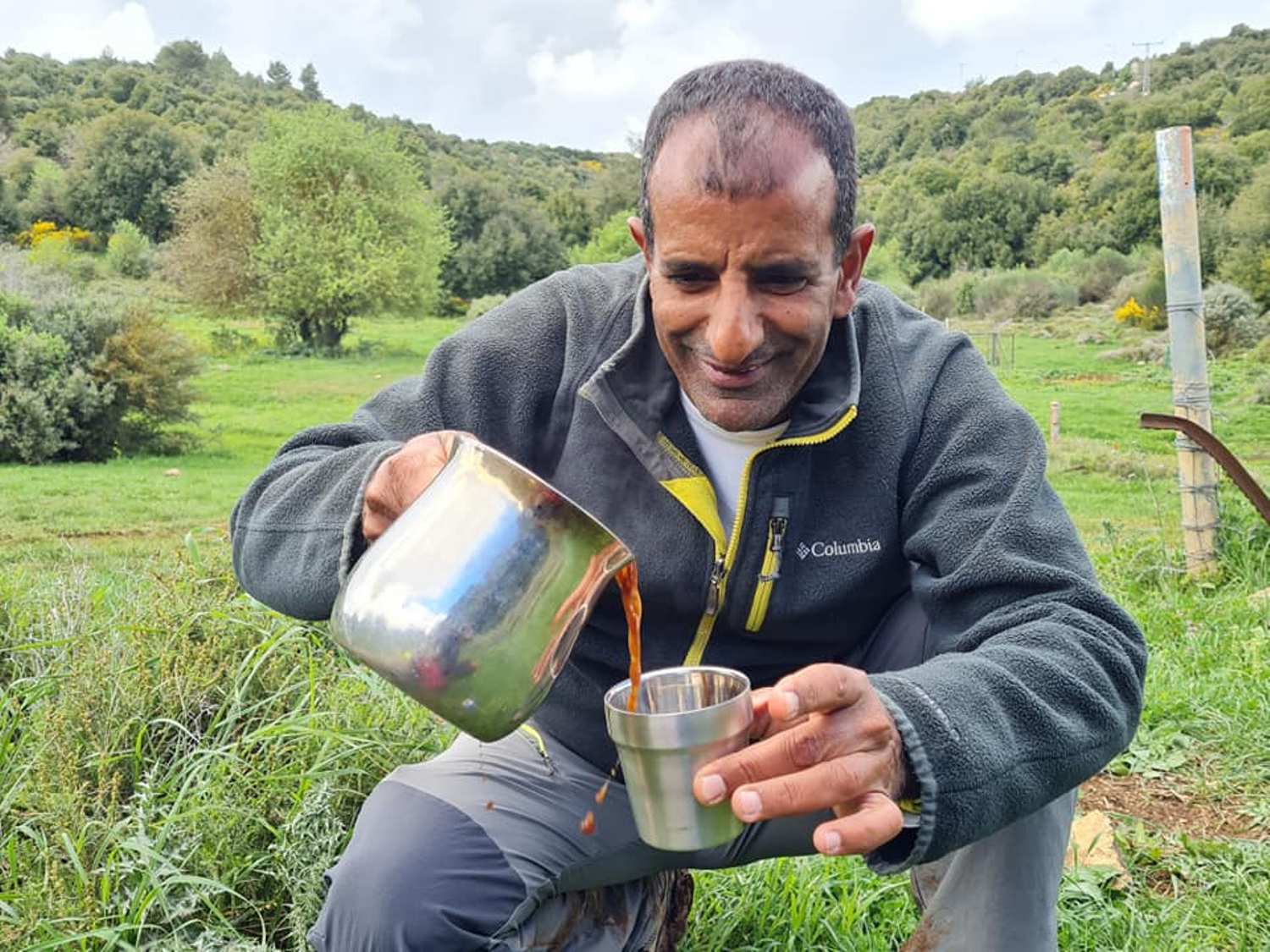 גבר מוזג קפה לכוס בשדה.