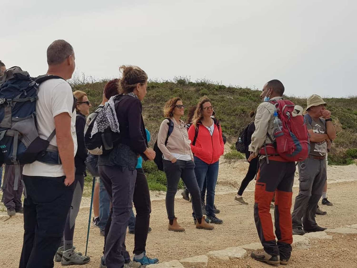 קבוצה של אנשים עם תרמילים עומדת על דרך עפר.