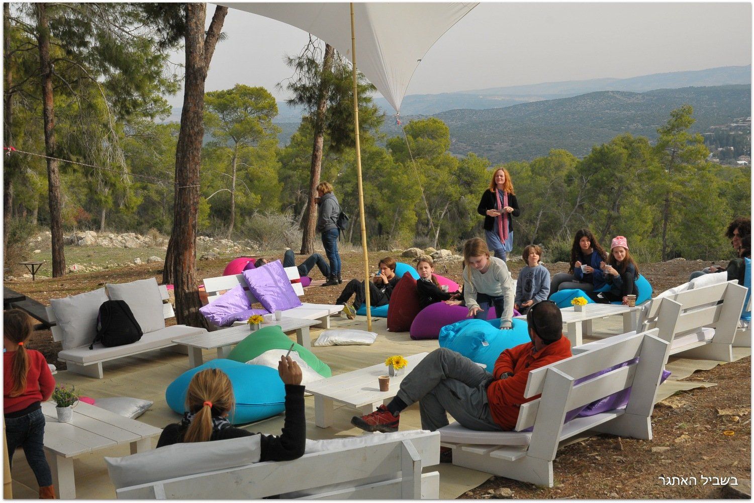 קבוצה של אנשים יושבת על כיסאות שקיות שעועית מתחת למטריה