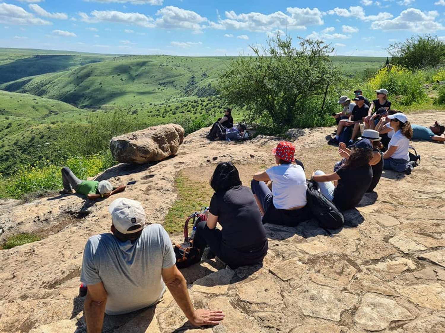 קבוצת אנשים יושבת על ראש גבעה סלעית.