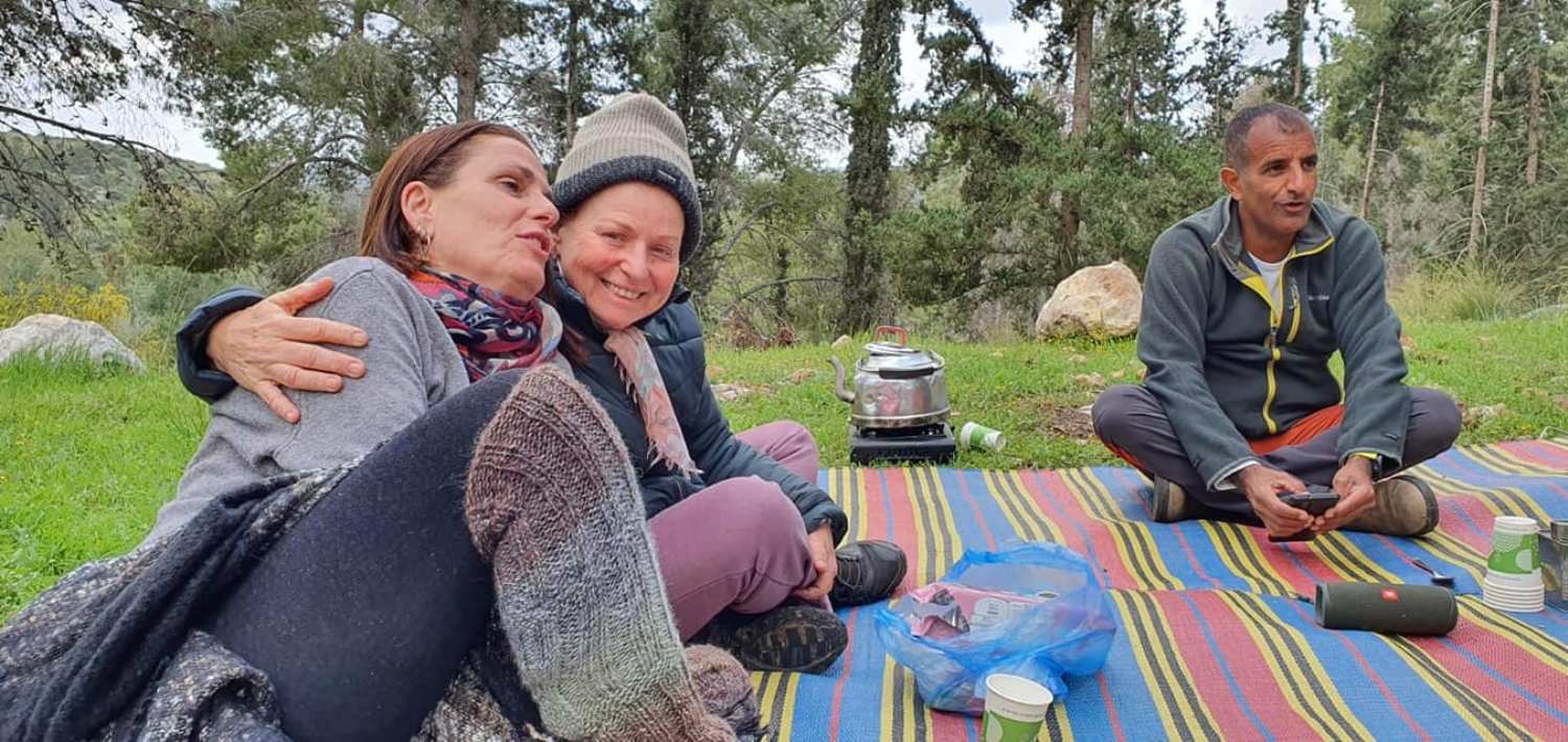 קבוצה של אנשים יושבת על שמיכה בדשא.