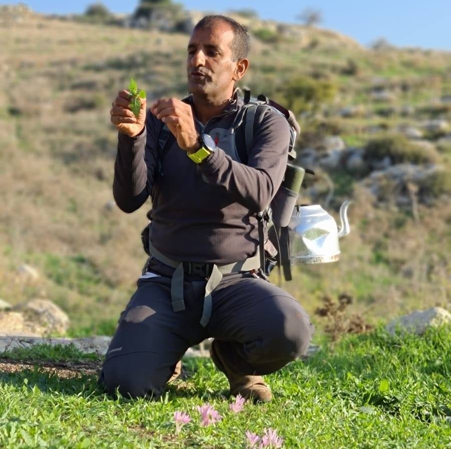 גבר עם תרמיל כורע בדשא