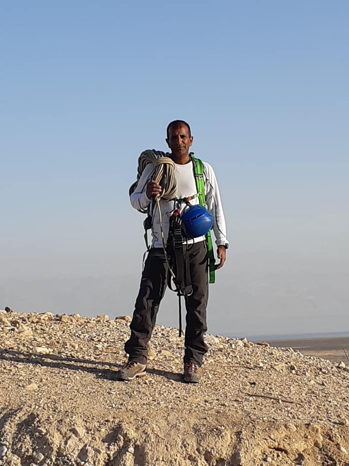 גבר עומד במדבר אוחז בקסדה כחולה ותרמיל.