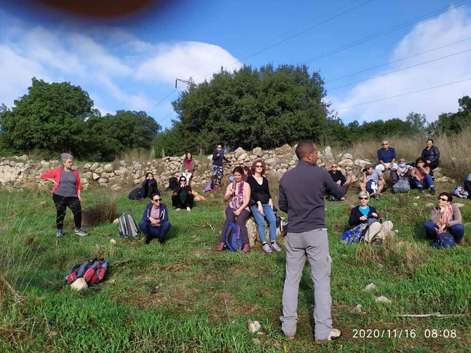 גבר עומד בשדה ומדבר עם קבוצת אנשים.