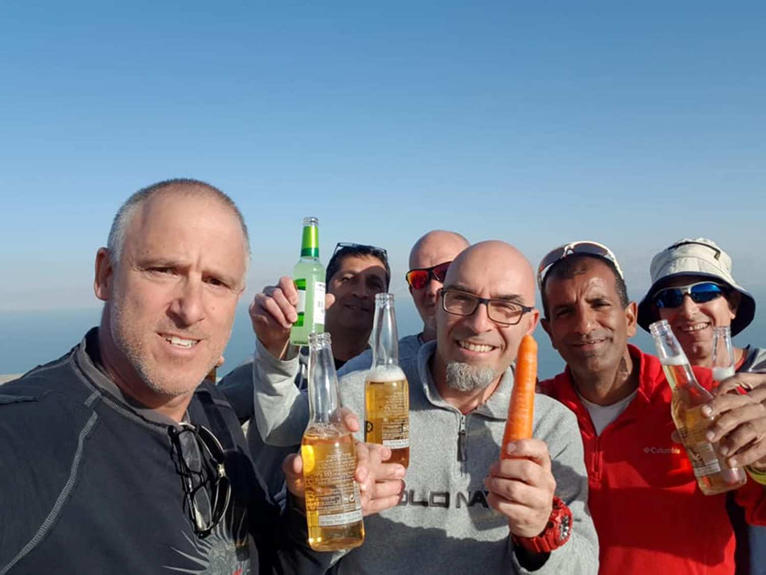 קבוצת גברים מחזיקה בקבוקי בירה וגזר.