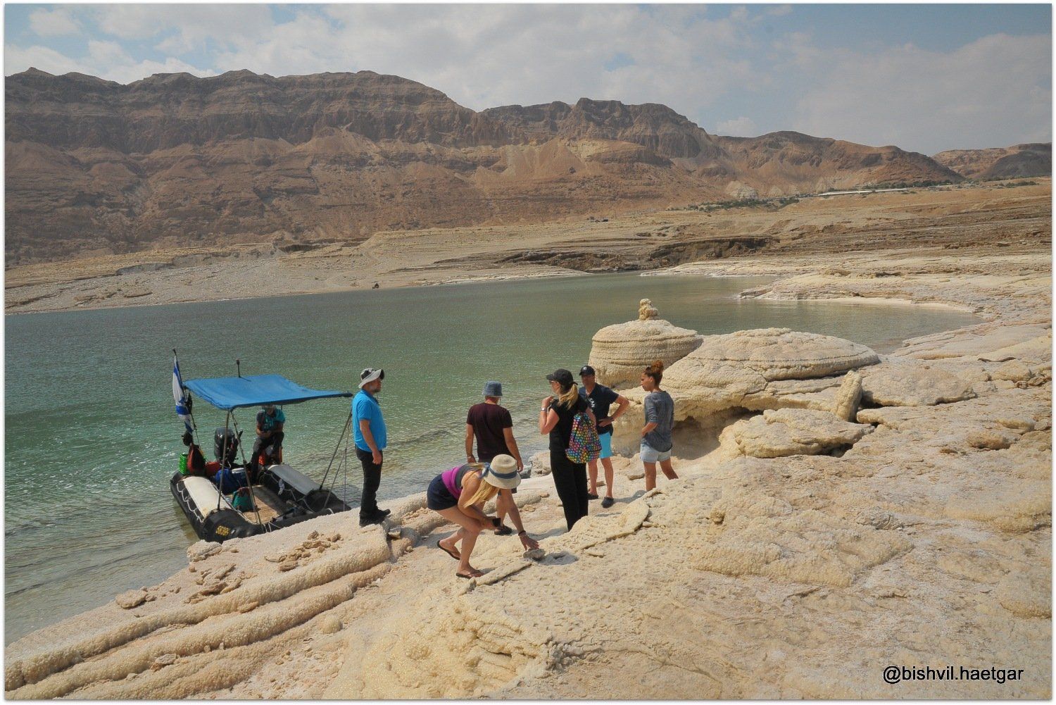 קבוצה של אנשים עומדת על חוף ליד סירה.