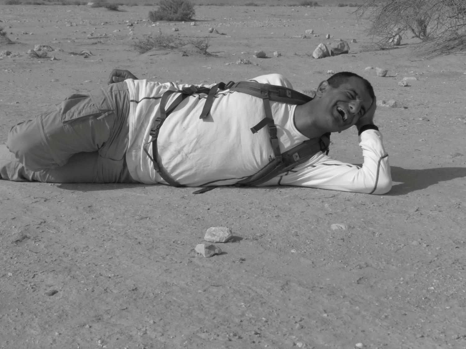 אדם עם תרמיל שוכב על האדמה במדבר