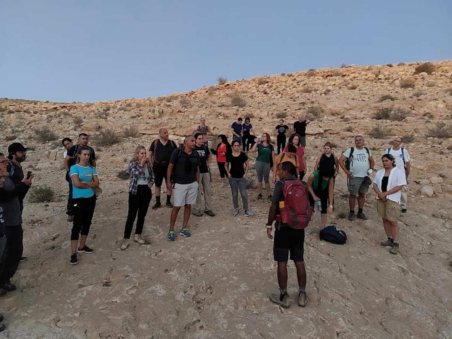 קבוצת אנשים עומדת במעגל במדבר.