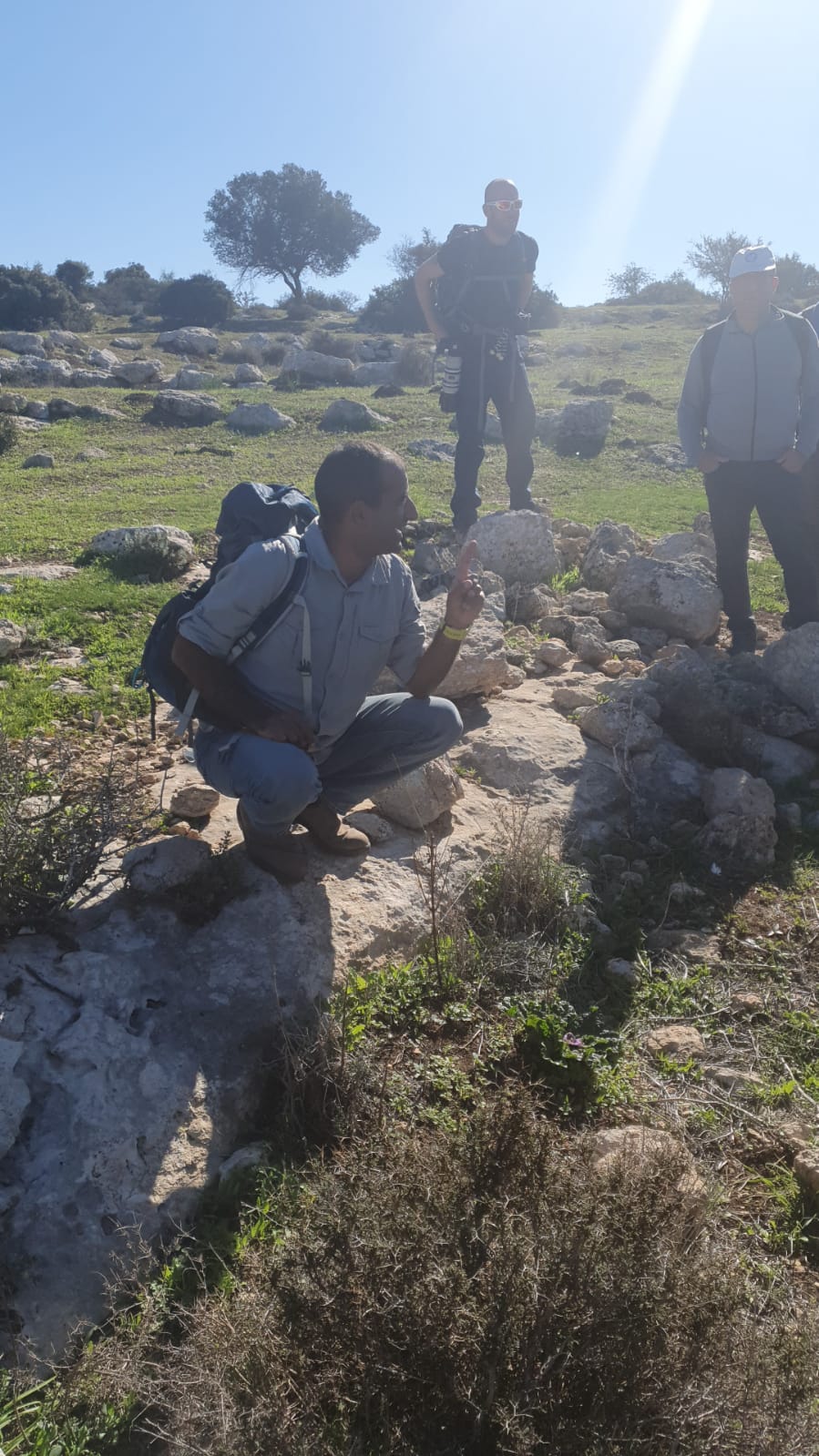 אדם עם תרמיל כורע על סלע בשדה.